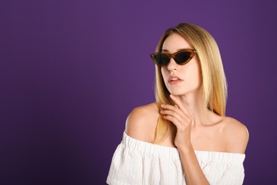 Beautiful woman in stylish sunglasses on purple background. Space for text