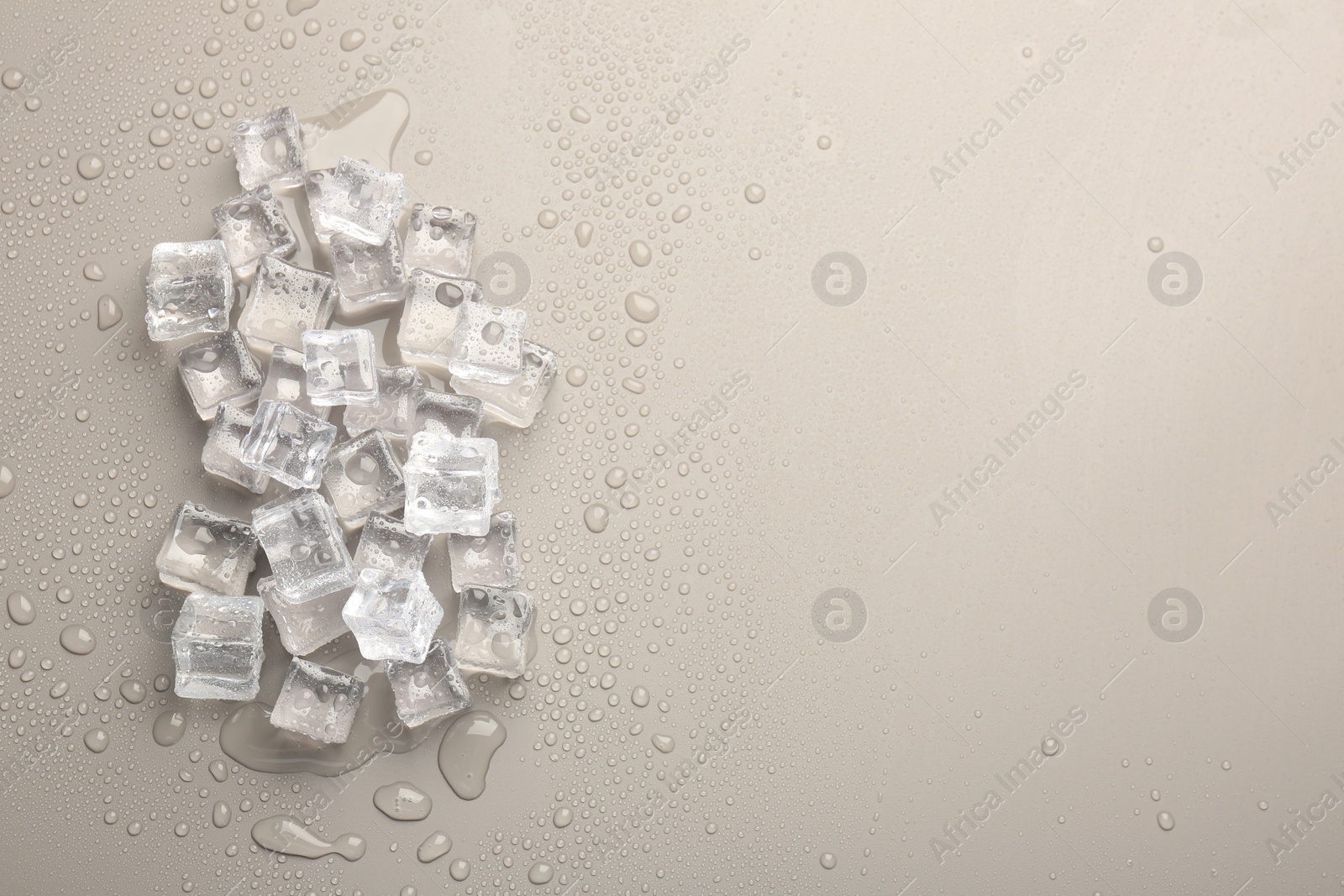 Photo of Melting ice cubes and water drops on light grey background, flat lay. Space for text
