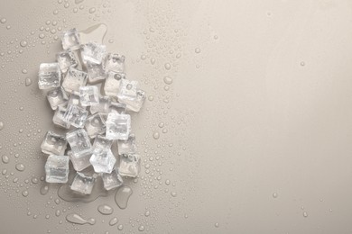 Melting ice cubes and water drops on light grey background, flat lay. Space for text