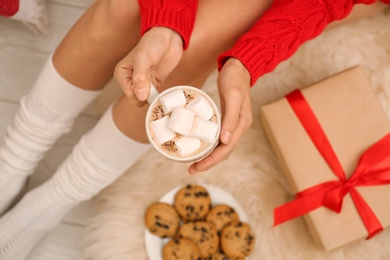 Young woman with cocoa sitting on floor, top view. Christmas holiday