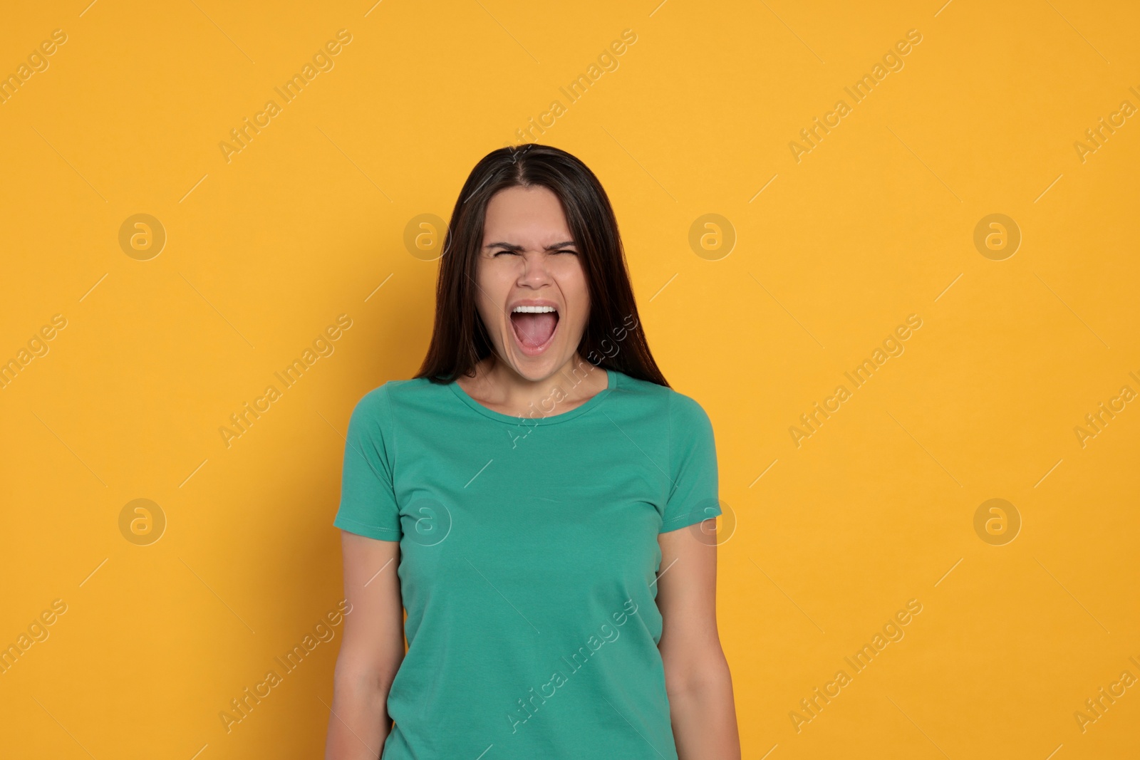 Photo of Aggressive young woman shouting on orange background