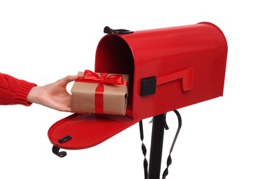 Photo of Woman putting Christmas gift into mailbox on white background, closeup. Sending present by mail