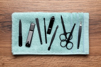 Set of manicure tools and towel on wooden table, top view