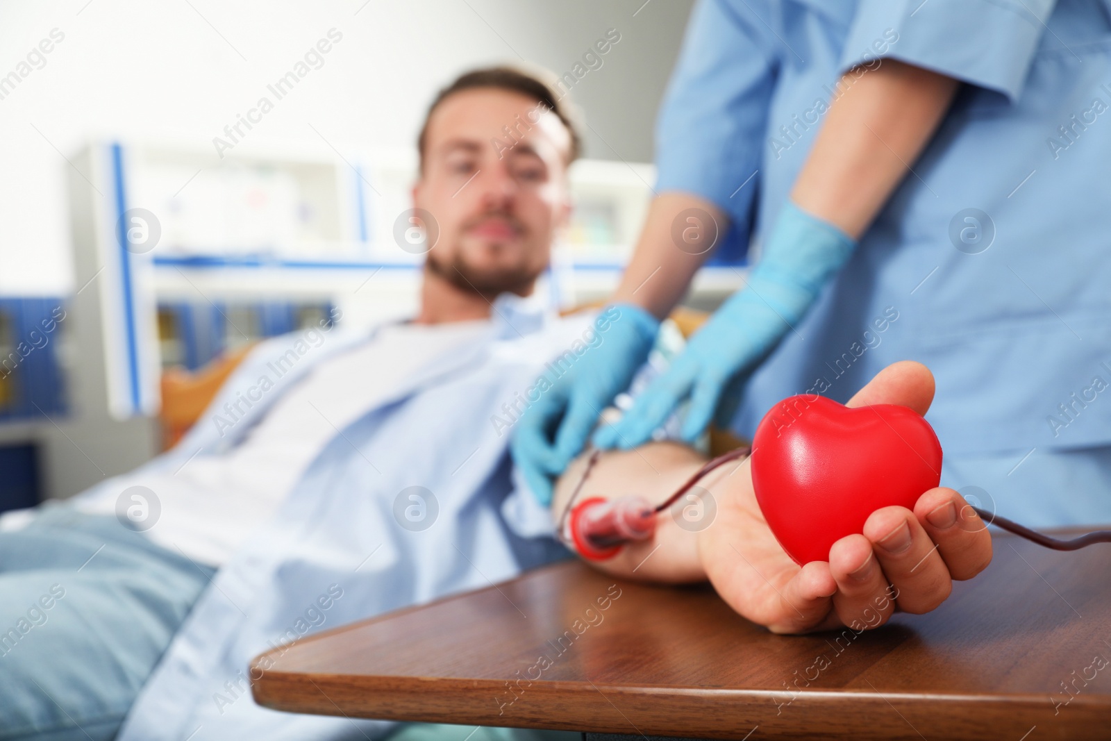 Photo of Young man making blood donation in hospital, focus on hand