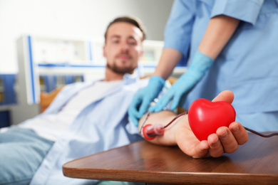 Young man making blood donation in hospital, focus on hand