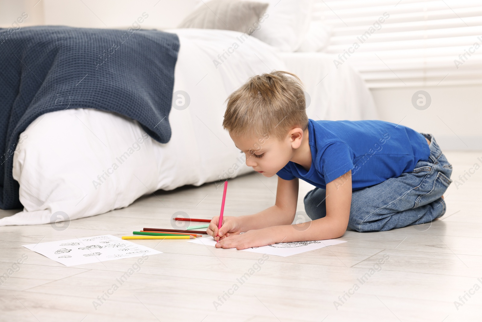 Photo of Cute little boy coloring on warm floor at home. Heating system