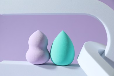 Stylish presentation of makeup sponges on violet background