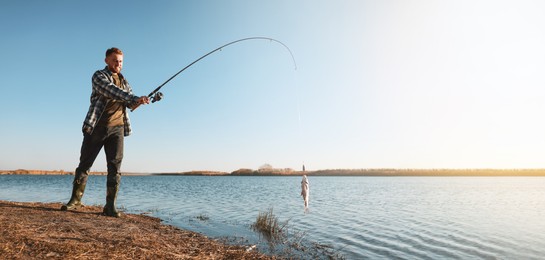 Image of Fisherman catching fish with rod at riverside, space for text. Banner design