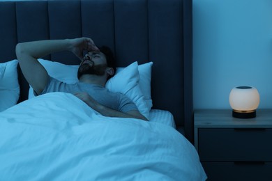 Man suffering from headache in bed at night