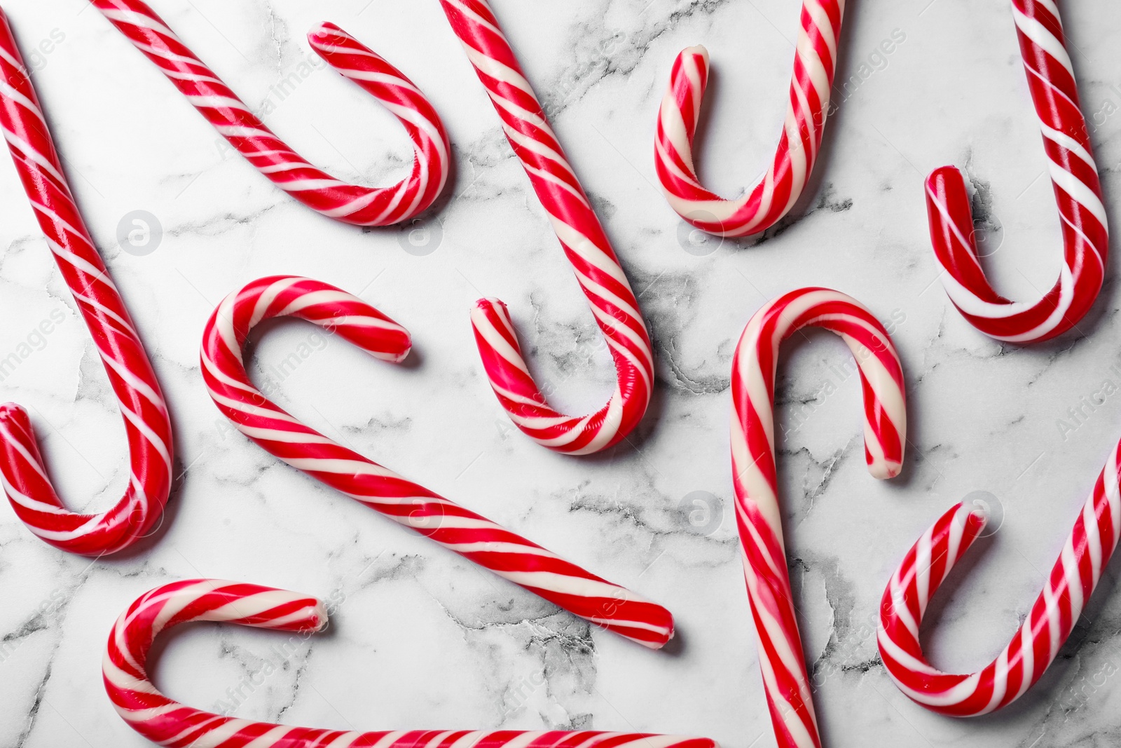 Photo of Sweet Christmas candy canes on white marble background, flat lay