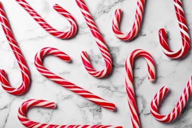 Photo of Sweet Christmas candy canes on white marble background, flat lay