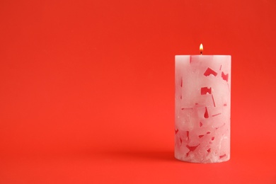 Alight wax candle on color background. Space for text