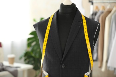 Photo of Mannequin with unfinished suit jacket and measuring tape in tailor shop