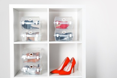 Photo of Footwear and plastic boxes on shelves near wall. Shoe storage organization