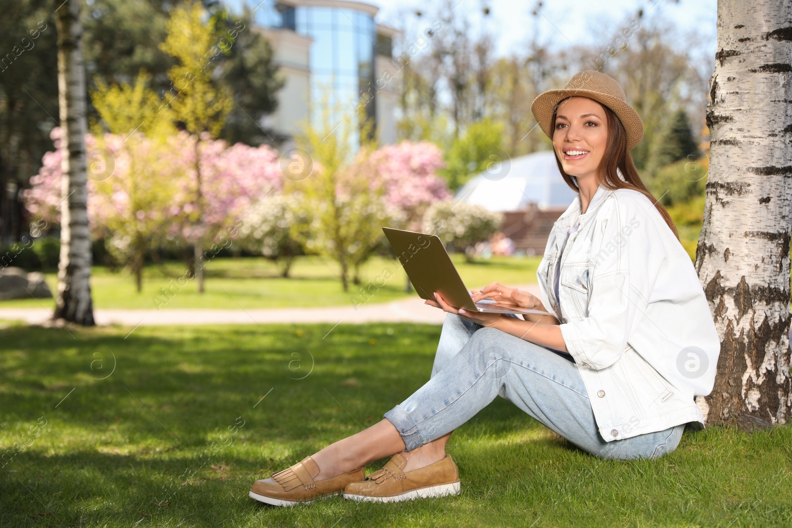 Photo of Woman working with laptop under tree in park. Space for text