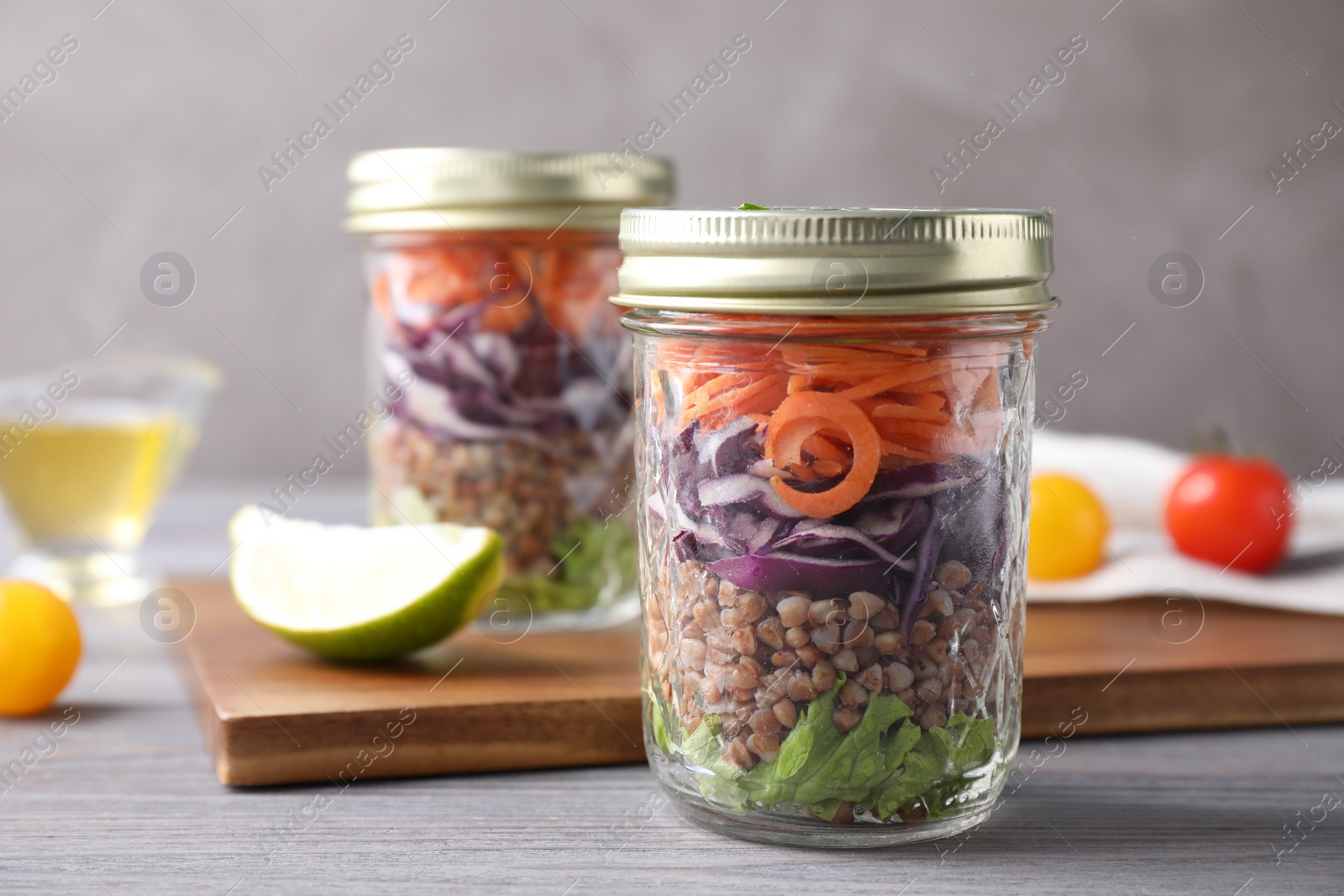 Photo of Glass jars with healthy meal on light grey wooden table