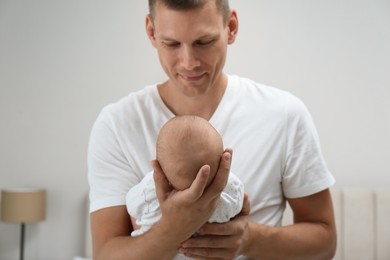 Happy father holding his cute baby at home