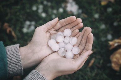 Woman holding hail grains after thunderstorm outdoors, closeup