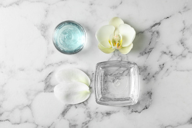 Flat lay composition with cosmetic gel and beautiful flowers on white marble table