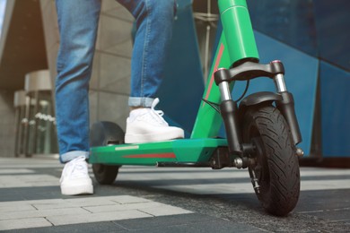 Photo of Woman with modern electric kick scooter outdoors, closeup