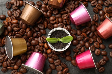 Photo of Coffee capsules with seedling and beans on black table, flat lay