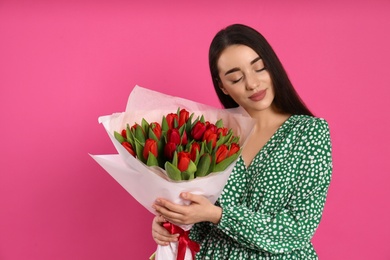 Photo of Happy woman with red tulip bouquet on pink background. 8th of March celebration
