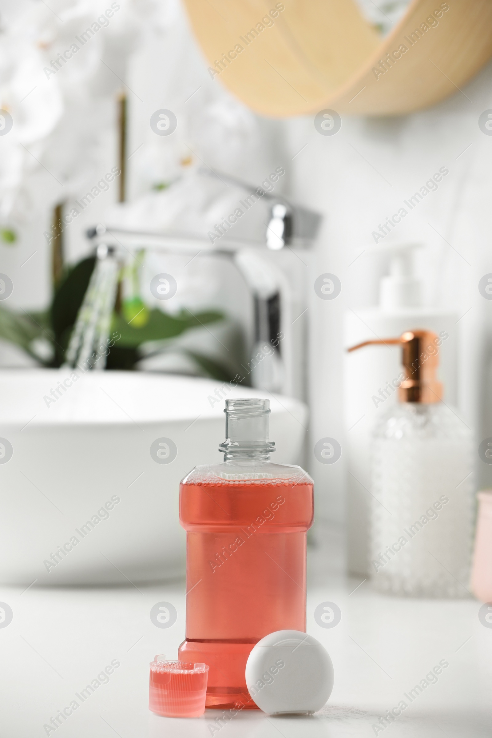 Photo of Mouthwash and dental floss on white countertop in bathroom