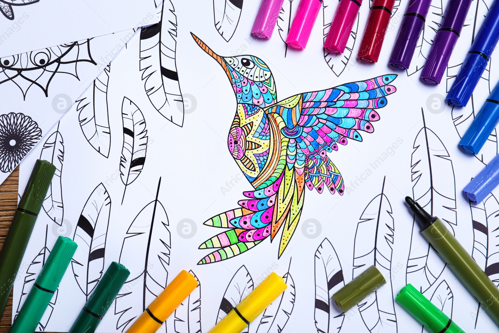 Photo of Felt tip pens on antistress coloring page, top view