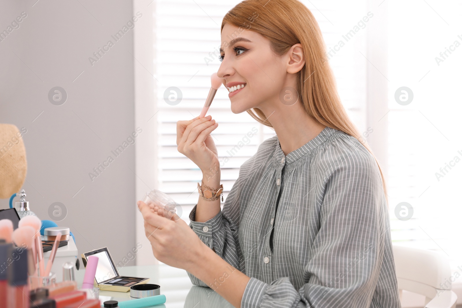 Photo of Beautiful young woman applying makeup in dressing room