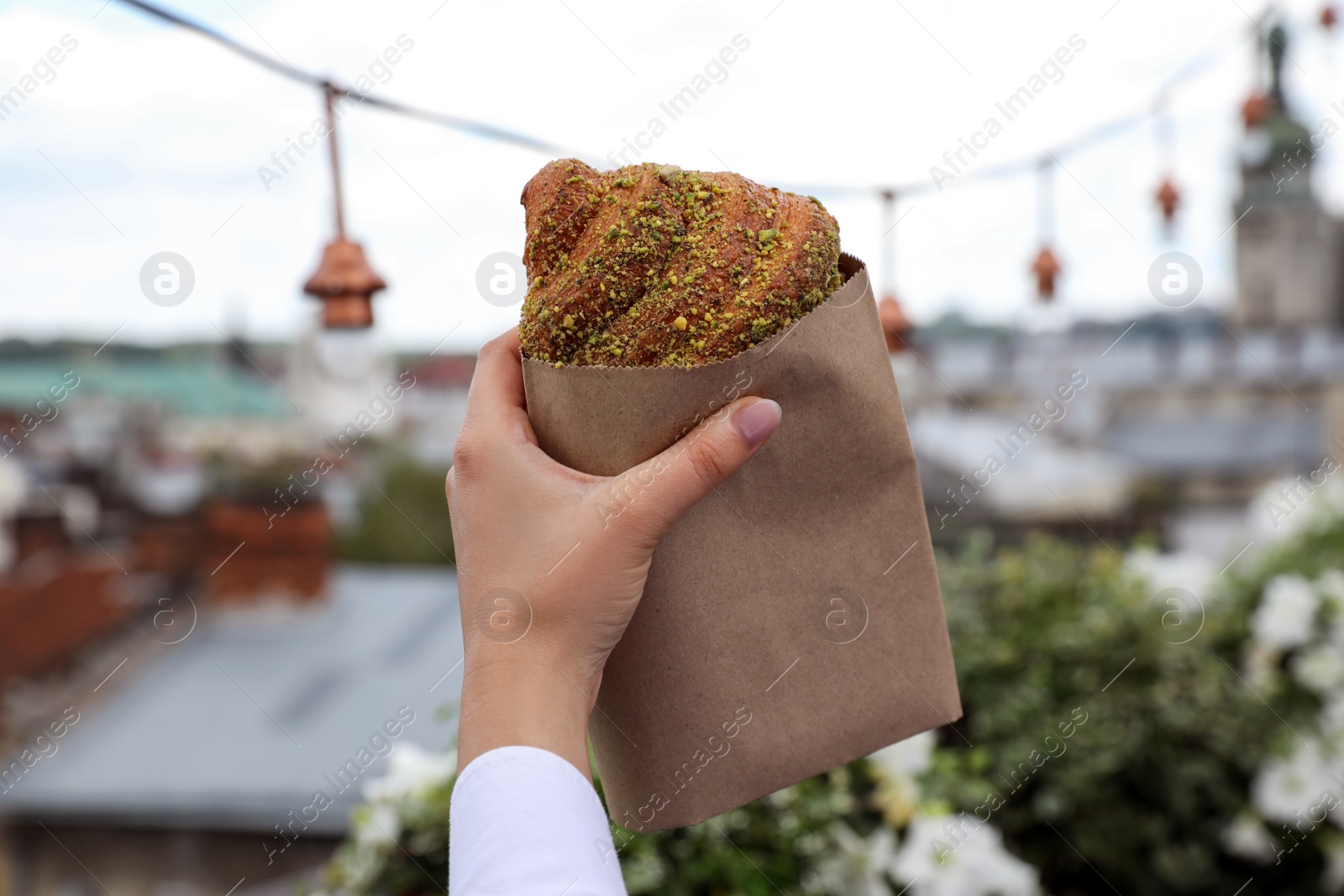 Photo of Woman with delicious croissant outdoors, closeup view