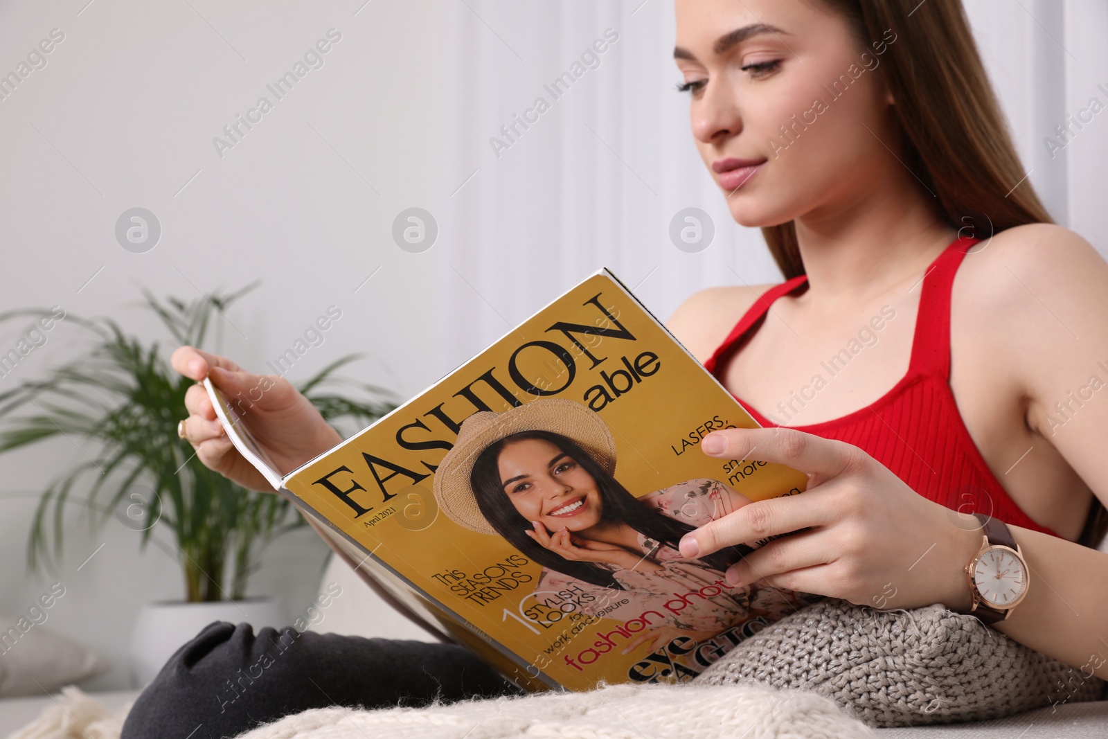 Photo of Young woman reading fashion magazine at home, closeup