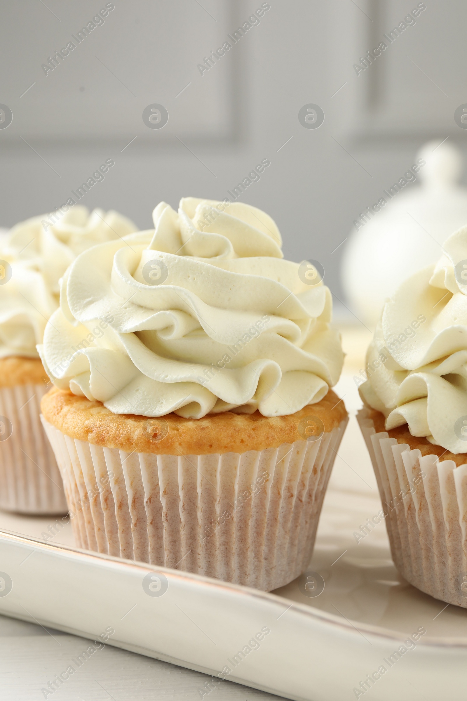 Photo of Tasty cupcakes with vanilla cream on white wooden table, closeup