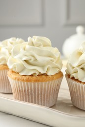 Tasty cupcakes with vanilla cream on white wooden table, closeup