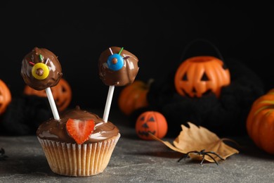 Photo of Delicious desserts decorated as monsters on grey table. Halloween treat