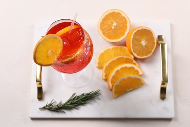 Photo of Glass of tasty Aperol spritz cocktail with orange slices and rosemary on white table, above view