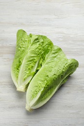Photo of Fresh green romaine lettuces on white wooden table, top view