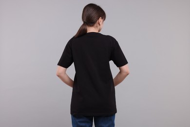 Woman in stylish black t-shirt light grey on background, back view