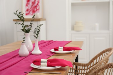 Photo of Beautiful table setting and vases with green branches in dining room