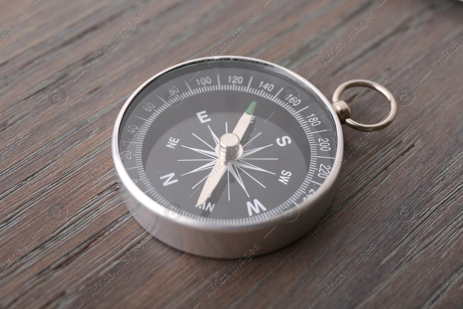 Photo of One compass on wooden table, closeup. Tourist equipment