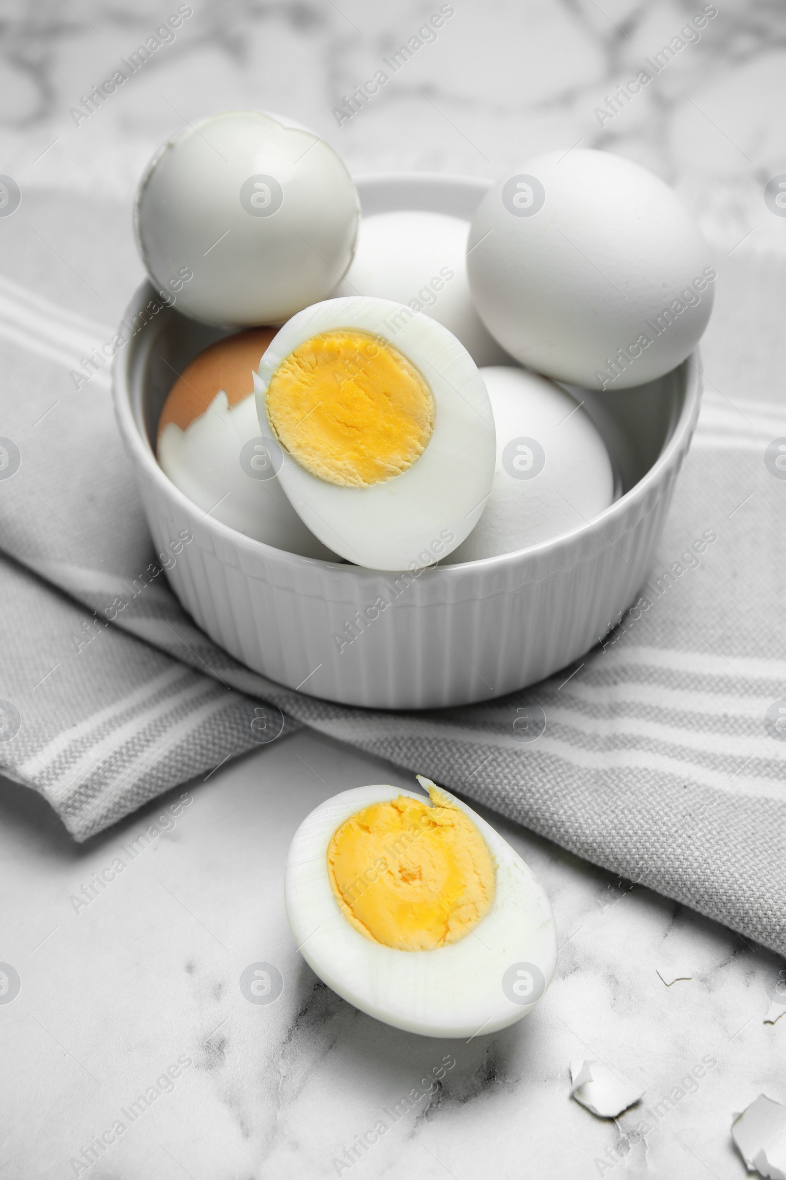 Photo of Bowl with hard boiled eggs on white marble table