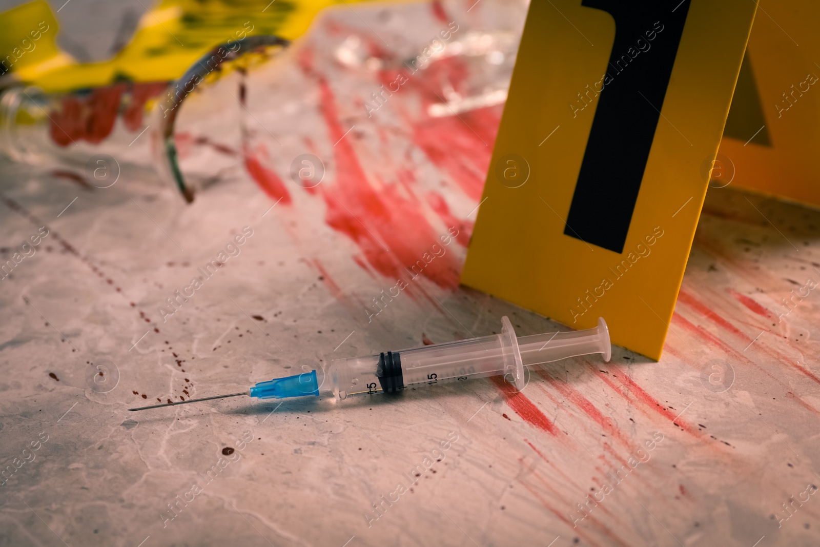 Photo of Syringe in blood and crime scene marker on marble table, closeup