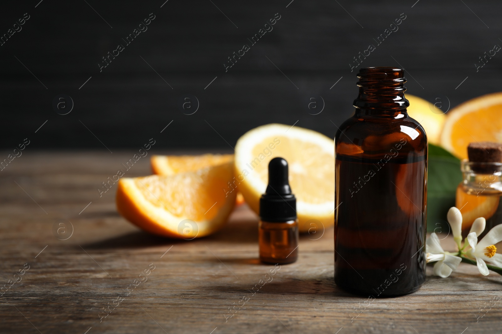 Photo of Bottles of citrus essential oil on wooden table. Space for text