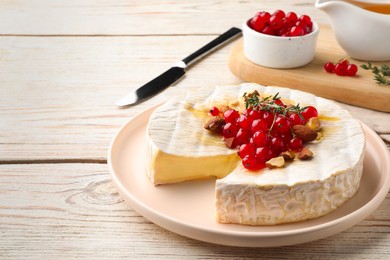 Photo of Brie cheese served with almonds, red currants and honey on white wooden table. Space for text