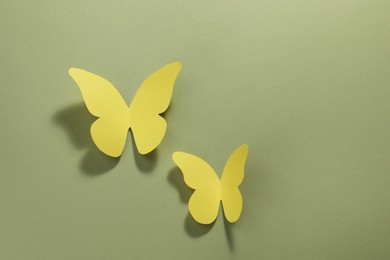 Photo of Yellow paper butterflies on pale green background, top view. Space for text