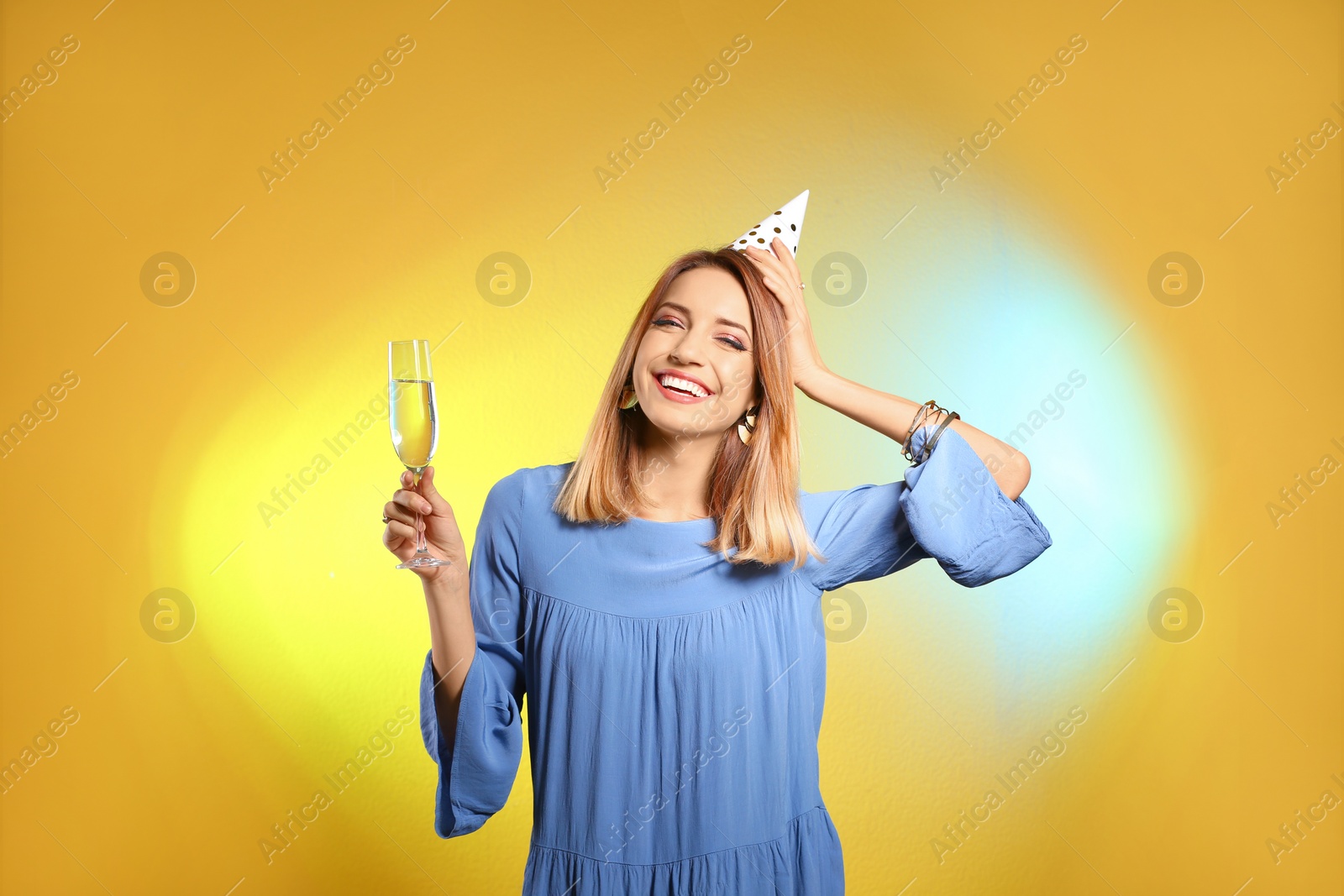 Photo of Portrait of happy woman with party hat and champagne in glass on color background