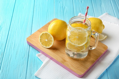 Mason jar with lemon water and fresh fruits on wooden board