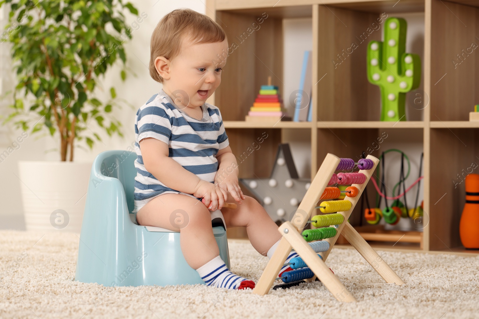 Photo of Little child with abacus sitting on plastic baby potty indoors