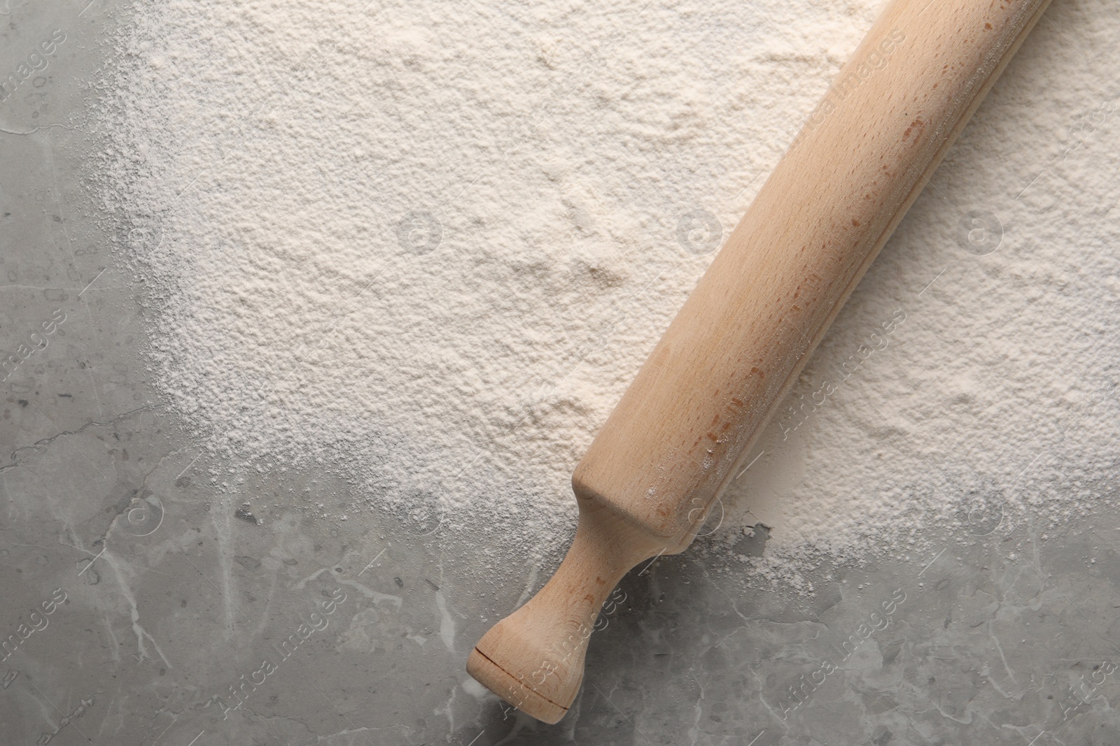 Photo of Pile of flour and rolling pin on grey marble table, top view