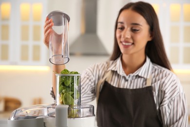 Photo of Young woman making tasty fresh juice in kitchen, focus on hand