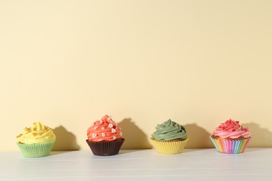 Photo of Delicious cupcake with bright cream on white wooden table. Space for text